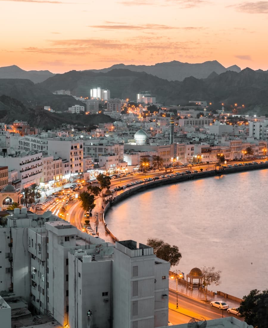 Muscat's Muttrah corniche curving along the bay at dusk